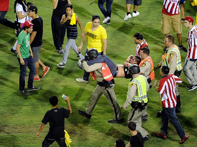 Un aficionado es cargado por dos policías, tras haberse metido al terreno de juego (AP) Un aficionado es cargado por dos policías, tras haberse metido al terreno de juego (AP)