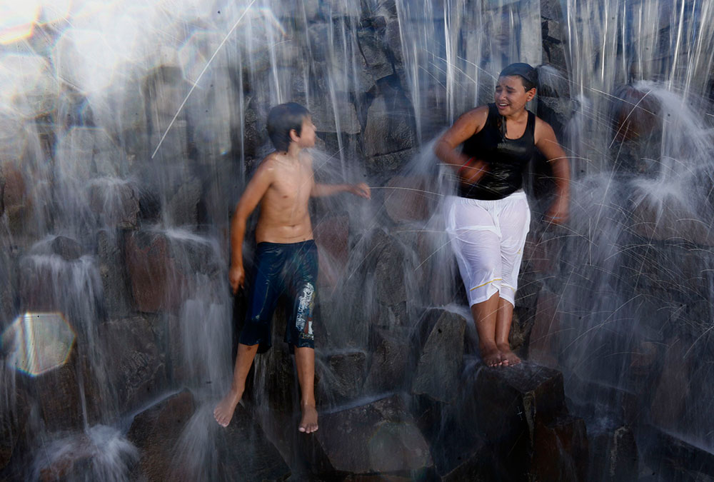 A divertirse. Dos personas juegan en una cascada que recrea las Cataratas de Iguazu. A divertirse. Dos personas juegan en una cascada que recrea las Cataratas de Iguazu.