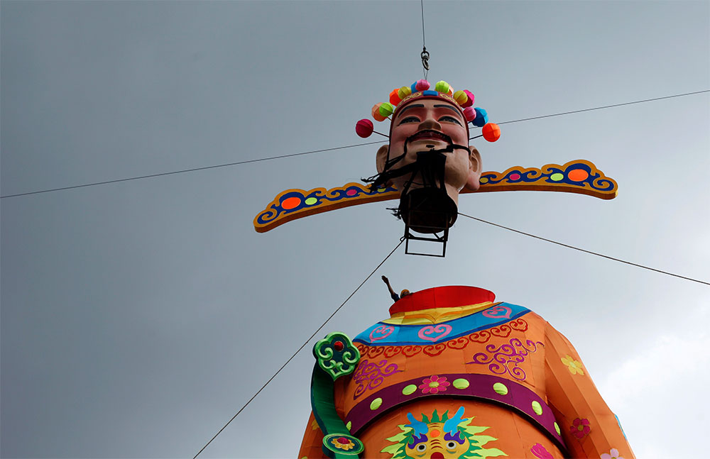 Viene, viene. Un trabajador dirige las maniobras para colocar la cabeza a una estatua gigante del Dios de la Fortuna, como parte de la decoración de los festejos del Año Nuevo chino, en Singapur.