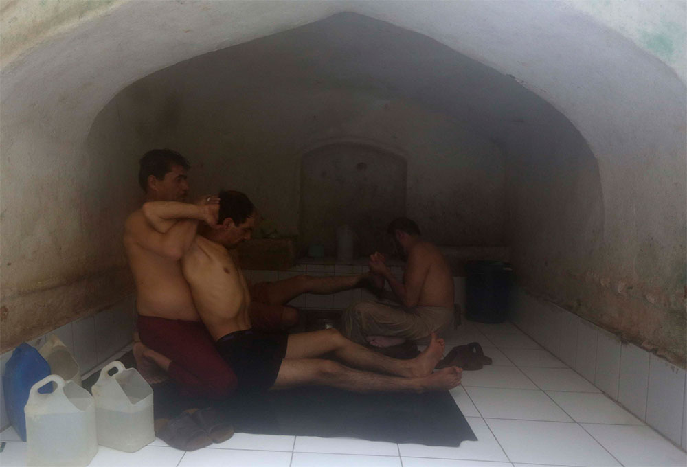 Un hombre da masaje a un cliente en un baño termal en la ciudad de Kabul.