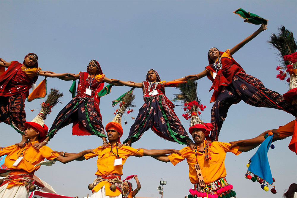 Hacen equilibrio. Bailarines vestidos con trajes tradicionales realizan una pirámide humana durante el festival internacional de papalotes en la ciudad india de Ahmedabad.