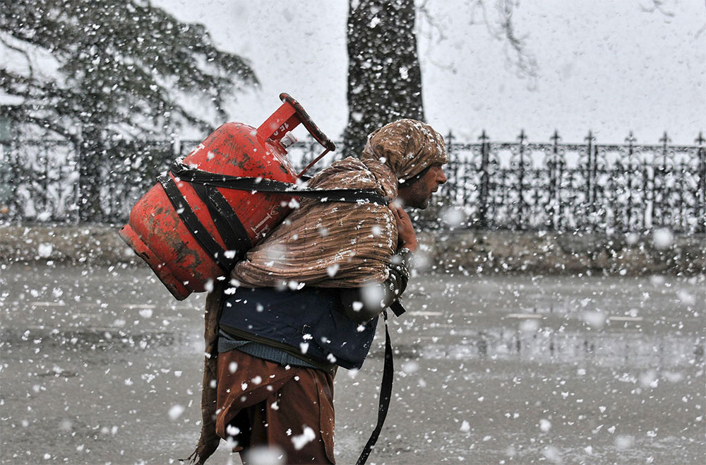 Carga Un hombre carga un cilindro de gas en medio de una fuerte nevada en el pueblo de Shimala, en India.