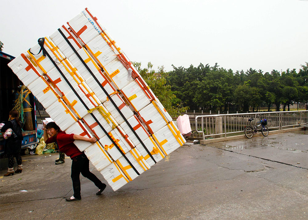 Fuerza femenina. Una mujer levanta un cargamento de cajas en una calle de la ciudad de Guangzhou, en China.
