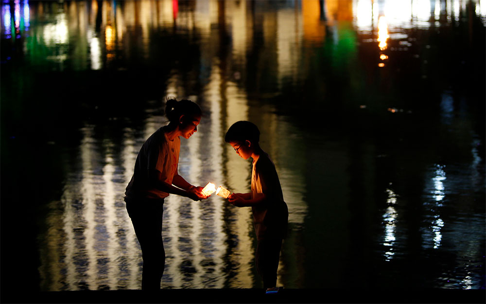 Momento familiar. Una madre y su hijo encienden una vela con motivo de la ceremonia “Una caminata nocturna en silencio”, en la ciudad de Kuala Lumpur, en Malasia.