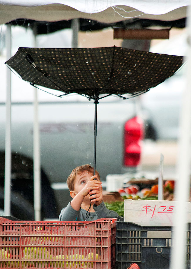 Al revés. Un niño sostiene un paraguas volteado por el viento en un mercado de Laguna Hills, California.