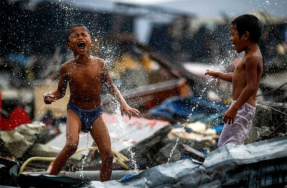 El agua es vida. Niños Filipinos aprovechan la fuga de agua de una tubería para refrescarse en la ciudad de Tacloban, en medio de los escombros dejados por el tifón Haiyan, que golpeó Filipinas el 8 de noviembre.