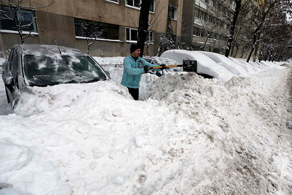 A ver si arranca. Un hombre retira la nieve acumulada sobre su automóvil en la ciudad de Bucarest, en Rumania, que en los últimos días ha sufrido los embates de un temporal de invierno.