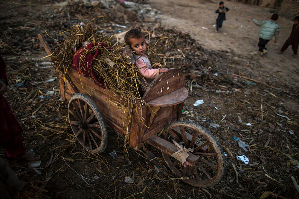 Un niño permanece sentado en una carreta en una barriada de Islamabad, en Pakistán.