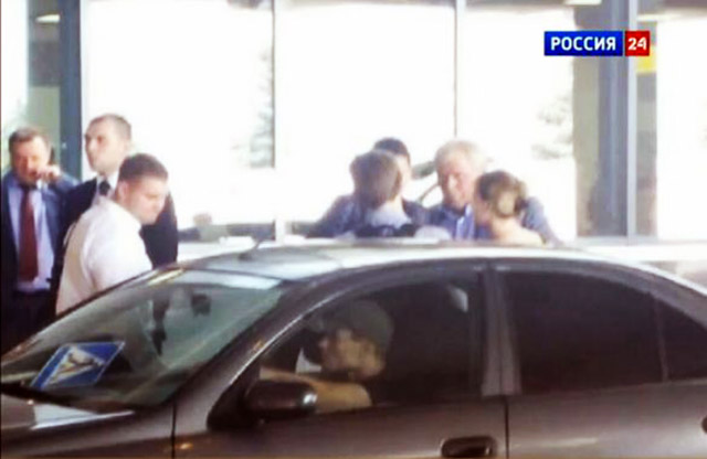 Edward Snowden (centro, al lado del auto) habla con su abogado Anatoly Kucherena mientras desaloja el aeropuerto de Sheremetyevo.